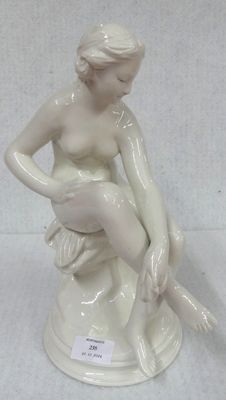 a white statue of a woman sitting on a rock