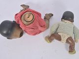 two small dolls sitting next to each other on a white surface