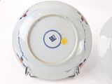 pair of blue and white plates with designs on them sitting on a table