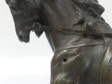 a bronze statue of a horse with a rider on it ' s back