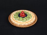 un petit gâteau garni de kiwis et de cerises
