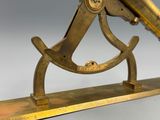 un télescope ancien en laiton posé sur un socle en bois, sur fond blanc
