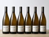 six bouteilles de vin blanc alignées sur une table en bois