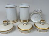 four white and gold vases with lids on a white table