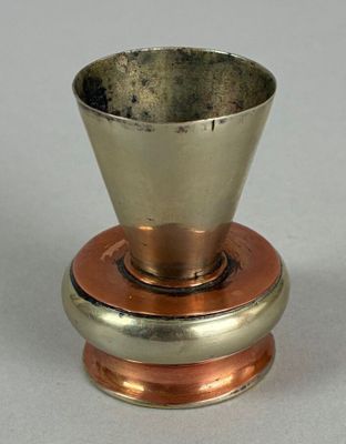 a silver cup on top of a copper plate