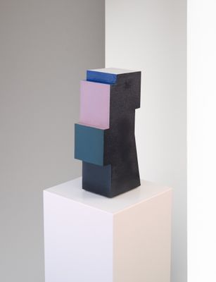 sculpture composée de blocs noirs, roses, bleus et blancs posés sur un socle blanc