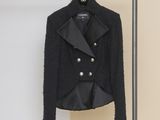 black jacket hanging on a hanger in front of a beige wall