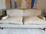 a white couch sitting in a living room with a painting on the wall