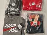 three t - shirts in plastic bags on a table
