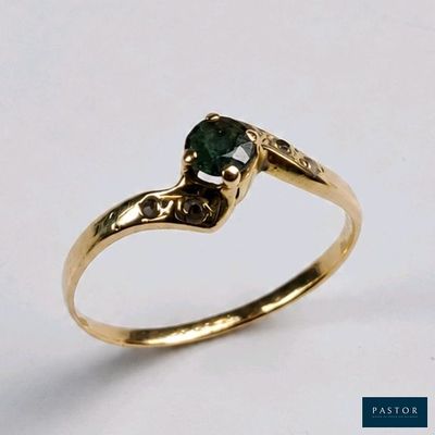 gros plan d'une bague en or avec une pierre verte