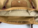 a tan bag with a brown handle on a white table