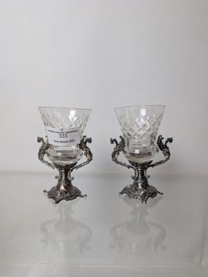pair of silver plated wine glasses on a glass table