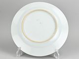 a white plate with a gold rim on a stand