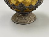 un vase en argent et en or posé sur une table blanche