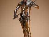 bronze statue of a man holding a knife and a sword