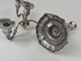 two silver candlesticks on a white table
