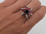 quelqu'un tient une bague sertie d'une pierre rouge et noire