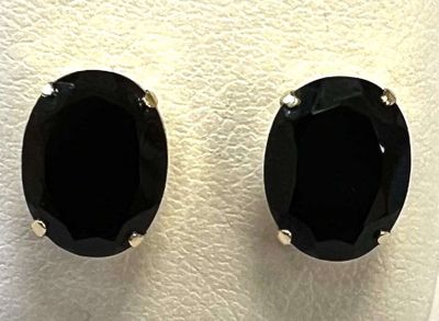 une paire de boucles d'oreilles à clous en pierre noire posées sur une surface blanche