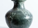 un vase vert posé sur une surface blanche