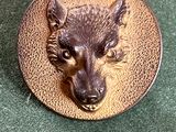 une photo d'une broche représentant une tête de loup sur un plateau