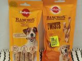 two bags of dog treats sitting on top of a bed