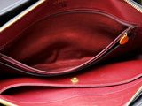 a black purse with a red lining and a gold zipper