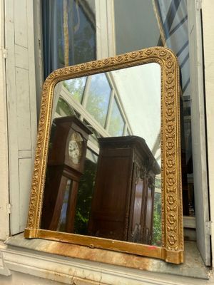 a mirror sitting on a window sill in front of a clock