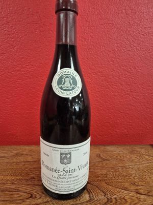 une bouteille de vin posée sur une table devant un mur rouge