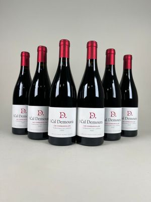 six bottles of red wine are lined up on a table