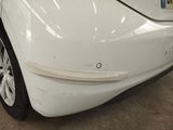 a white car that has been dented and is parked in a garage
