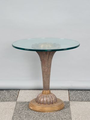 une photo d'une table en verre avec un piètement doré posée sur un sol en damier