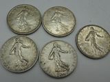 six silver coins of different sizes and shapes on a white surface