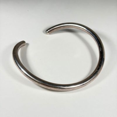 gros plan d'un bracelet métallique sur une surface blanche