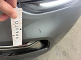 a person holding a measuring tape on the front of a car