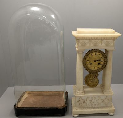 une horloge sous un dôme en verre, à côté d'une petite boîte