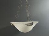 a white bowl hanging from a chain on the wall