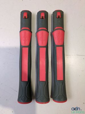 trois outils noirs et rouges posés sur une table blanche