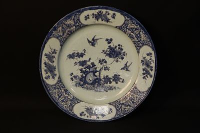 a blue and white plate with birds and flowers on it