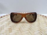 brown sunglasses on top of a woven basket on a white surface