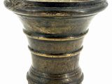 un grand vase en métal posé sur un socle, sur une surface blanche