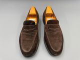 une paire de chaussures en daim marron posées sur une surface blanche