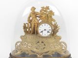 a gold clock under a glass dome on a table