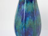 a blue and green vase sitting on a white surface