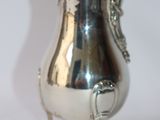 a silver tea pot on a stand on a white surface