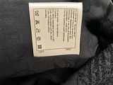 the label on the back of a black jacket with a white tag