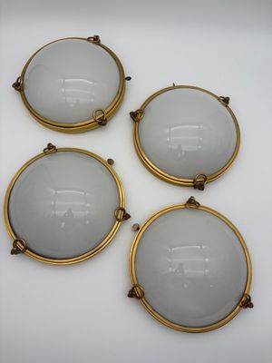 un ensemble de quatre appliques murales en laiton plaqué, dotées d'abat-jours en verre dépoli