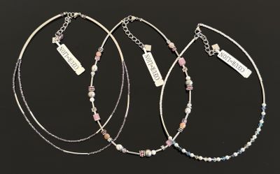 trois bracelets en argent ornés de perles roses et bleues sur fond noir