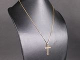 un collier avec une croix en or autour du cou d'un mannequin