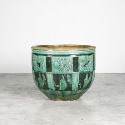 une image représentant un grand vase vert posé sur un sol en béton