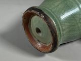 a green vase that is sitting on a white surface